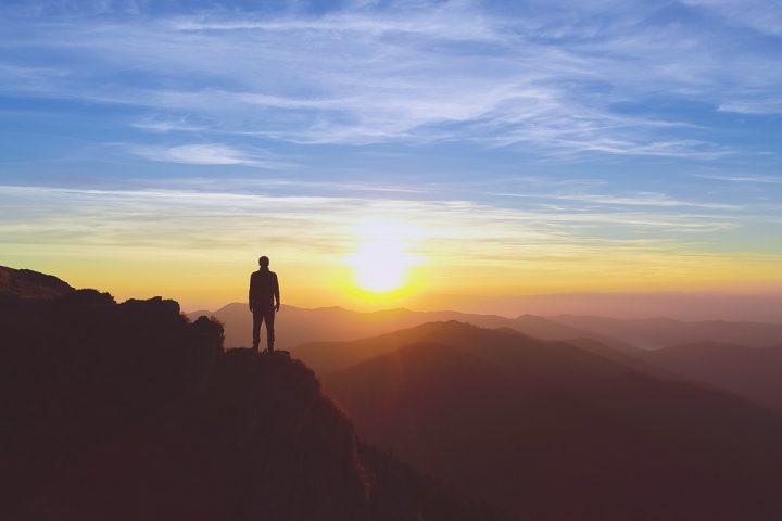 The man standing on the mountain on the picturesque sunrise background